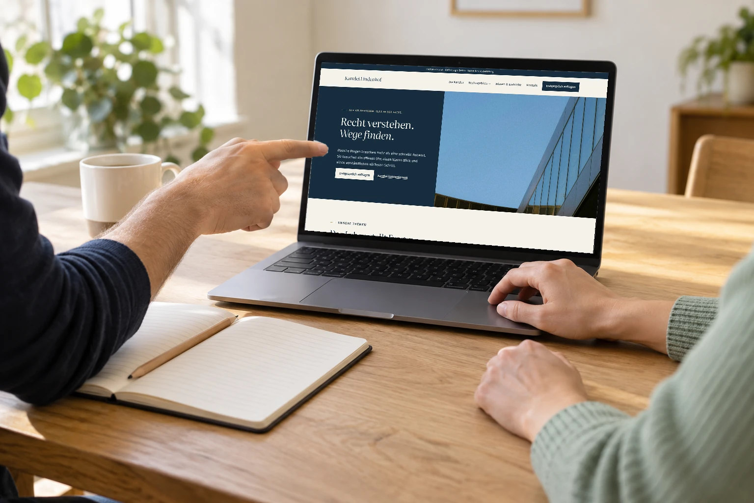 Symbolische Zusammenarbeit: zwei Menschen stimmen einen Website-Entwurf am Laptop ab